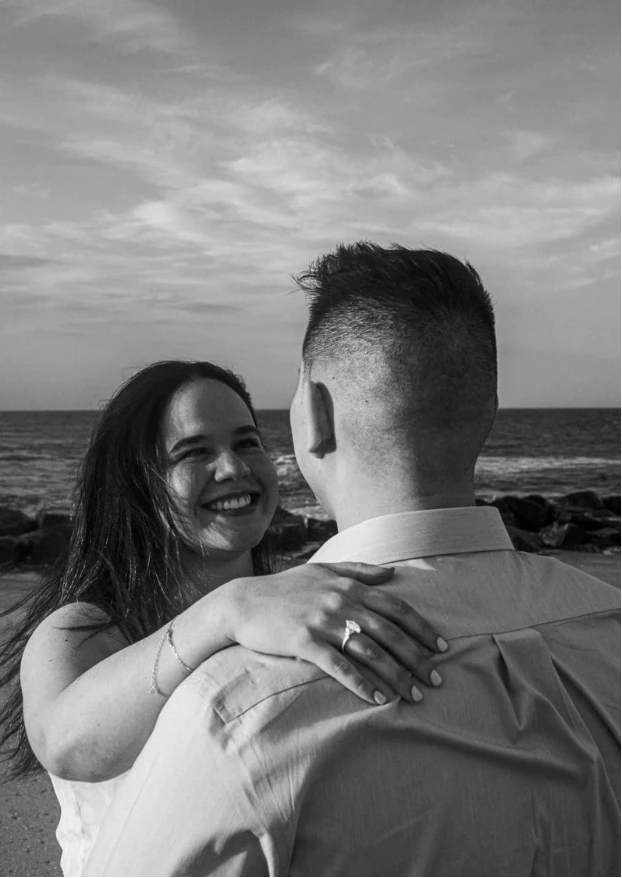 Sofia laughing as she embraces Carlos by the ocean.